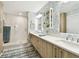 Bathroom featuring double sinks, a glass-enclosed shower, and white and blue patterned wallpaper at 415 Island Way # 507, Clearwater Beach, FL 33767