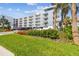 Modern condominium building featuring multiple balconies, a landscaped lawn, and convenient parking at 415 Island Way # 507, Clearwater Beach, FL 33767