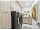 Modern laundry room with front loading machines, light wood cabinets, and a folding counter at 415 Island Way # 507, Clearwater Beach, FL 33767