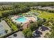 Aerial view of the community pool, clubhouse, and parking area, all surrounded by mature trees and landscaping at 4510 Beaumaris Dr, Land O Lakes, FL 34638