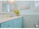 Charming bathroom with a bright blue vanity, quartz countertop and decorative tile accents at 511 Windward Psge, Clearwater Beach, FL 33767