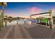 Dock view at twilight showcases waterfront living with a boat lift, charming lights, and serene water at 511 Windward Psge, Clearwater Beach, FL 33767