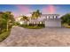 Elegant home showcasing a circular driveway, lush landscaping, and an attached two-car garage at 511 Windward Psge, Clearwater Beach, FL 33767