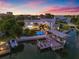 A waterfront estate with a pool, dock, boat lift, and backyard, set against a colorful sunset sky at 511 Windward Psge, Clearwater Beach, FL 33767