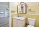 Bathroom with vanity and toilet, featuring unique yellow wall paneling and view into bedroom at 516 Northmoor N Ave, St Petersburg, FL 33702