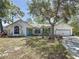 Lovely single-Gathering home featuring a green lawn, mature trees, and an attached two-car garage at 5323 73Rd N St, St Petersburg, FL 33709