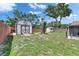 Backyard with a storage shed, mature tree, and lawn area enclosed by a charming wooden fence at 8445 Angela Ct, Zephyrhills, FL 33541