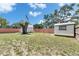 Spacious backyard with an American flag, a mature tree, sheds, and a wooden fence at 8445 Angela Ct, Zephyrhills, FL 33541