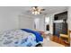 Bedroom view with doorway to bathroom, window and hardwood floors, ceiling fan and TV at 8445 Angela Ct, Zephyrhills, FL 33541