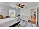 Bedroom with a ceiling fan, window and hardwood floors, leading to hallway at 8445 Angela Ct, Zephyrhills, FL 33541