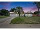 Charming home featuring a well-manicured front yard, a palm tree, and an attached two-car garage, at dusk at 8445 Angela Ct, Zephyrhills, FL 33541