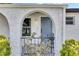 Charming front porch with an arched doorway, flowers, decorative tile, and wrought iron details at 8445 Angela Ct, Zephyrhills, FL 33541