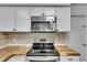 Kitchen area with stainless steel oven and microwave and neutral tile backsplash at 8445 Angela Ct, Zephyrhills, FL 33541