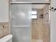 Shower stall with glass doors, window, neutral tile, and shower accessories for a luxurious bathing experience at 8445 Angela Ct, Zephyrhills, FL 33541