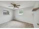 Neutral bedroom with carpet, ceiling fan, a small shelf, and two windows letting in natural light at 9011 Hunt Club Ln, Port Richey, FL 34668