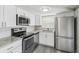 Well-lit kitchen with white cabinets, stainless steel appliances, gray countertops, and modern gray flooring at 9011 Hunt Club Ln, Port Richey, FL 34668
