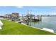 Waterfront view of private dock with boat lift and spacious backyard with green lawn at 905 Bay Point Dr, Madeira Beach, FL 33708