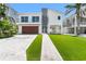 Modern two-story home with a wood garage door, landscaped yard and light brick driveway at 905 Bay Point Dr, Madeira Beach, FL 33708