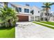 Modern two-story home with a wood garage door, landscaped yard and light brick driveway at 905 Bay Point Dr, Madeira Beach, FL 33708