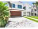 Modern two-story home with a wood garage door, landscaped yard and light brick driveway at 905 Bay Point Dr, Madeira Beach, FL 33708