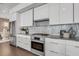 Modern kitchen featuring stainless steel appliances and sleek white cabinetry with gray backsplash at 905 Bay Point Dr, Madeira Beach, FL 33708