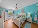 Bright bedroom with tropical patterned bedding, ceiling fan, wood floors, and turquoise accent wall at 920 Tuscanny St, Brandon, FL 33511