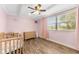 Light pink bedroom featuring a crib, dresser, and natural light from the window at 9819 Allen Rd, Lithia, FL 33547