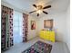 Bright bedroom featuring colorful accents, a modern ceiling fan, and large window with floral curtains at 7516 S Mascotte St, Tampa, FL 33616