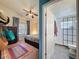 Bedroom leading into ensuite bath features a tranquil setting with natural light, ceiling fan and unique decor at 7516 S Mascotte St, Tampa, FL 33616