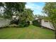 Lush backyard featuring a well-manicured lawn, mature trees, and privacy fencing at 11322 Carrollwood Dr, Tampa, FL 33618
