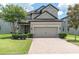 Well-maintained two-story house featuring a brick driveway and mature landscaping in front at 12382 Tibbetts St, Odessa, FL 33556