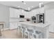Open-concept kitchen with white cabinets, a large island with bar seating, and stainless steel appliances at 12382 Tibbetts St, Odessa, FL 33556