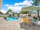 Inviting outdoor pool area features lounge chairs, a dining table with umbrella, and lush landscaping at 13186 Linden Place Dr, Seminole, FL 33776
