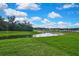 Expansive backyard view overlooking a pond with green grass and mature trees, perfect for relaxation and outdoor activities at 13648 Whiskey Daisy Dr, Dade City, FL 33525