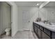 Bathroom featuring a double vanity with dark cabinets, two sinks, toilet and grey tile flooring at 13648 Whiskey Daisy Dr, Dade City, FL 33525