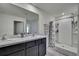 Bathroom featuring a double vanity with dark cabinets, two sinks, and shower with tile surround at 13648 Whiskey Daisy Dr, Dade City, FL 33525