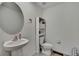 Modern powder room featuring a pedestal sink, decorative mirror, and neutral color scheme at 13648 Whiskey Daisy Dr, Dade City, FL 33525