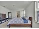 Well-lit bedroom with neutral walls, a TV stand, and a bed with a decorative blue and white patterned cover at 13648 Whiskey Daisy Dr, Dade City, FL 33525