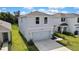 Two-story home with manicured lawn and two-car garage, surrounded by lush greenery at 13648 Whiskey Daisy Dr, Dade City, FL 33525