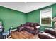 A living room featuring green walls, hardwood floors, and comfortable brown leather seating at 13648 Whiskey Daisy Dr, Dade City, FL 33525