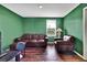 A living room featuring green walls, hardwood floors, and comfortable brown leather seating at 13648 Whiskey Daisy Dr, Dade City, FL 33525