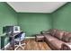 A living room featuring green walls, hardwood floors, comfortable seating, and a black desk at 13648 Whiskey Daisy Dr, Dade City, FL 33525