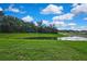 Expansive backyard with a peaceful pond, lush greenery, and neighborhood views at 13648 Whiskey Daisy Dr, Dade City, FL 33525