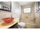 Bathroom featuring vessel sink, tan tiling, and shower-tub combo with decorative tile accents at 1510 Patricia Ave, Dunedin, FL 34698