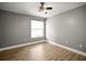Bedroom with wood-look flooring, gray walls, a ceiling fan, and a bright window at 1510 Patricia Ave, Dunedin, FL 34698
