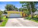 The yellow home features a white garage door and a well-manicured front yard with flowering plants at 1510 Patricia Ave, Dunedin, FL 34698