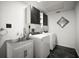 Modern laundry room featuring black and white design, stainless steel sink, and front loading washer/dryer at 1510 Patricia Ave, Dunedin, FL 34698