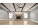 Open living room featuring wood beams, a stone fireplace, two windows, and laminate wood flooring at 1510 Patricia Ave, Dunedin, FL 34698