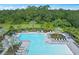 Community pool featuring lounge chairs, tables with umbrellas, palm trees, and nearby wooded area at 16427 Sapphire Point Dr, Lakewood Ranch, FL 34211