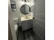 Updated bathroom with a round mirror, wood-look flooring, and a modern vanity with marble-look countertops at 19743 Ellendale Dr, Land O Lakes, FL 34638